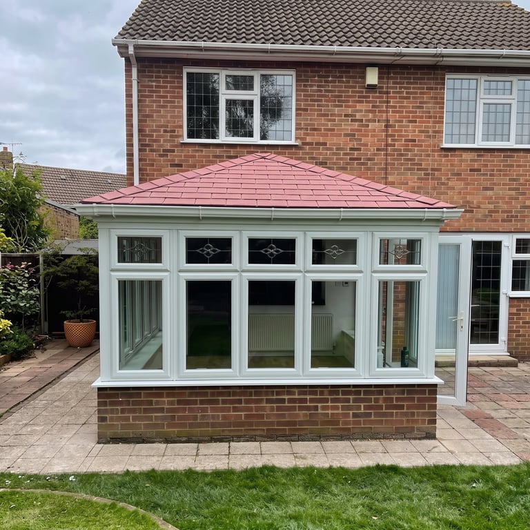 After: White-framed conservatory with pink tiled roof attached to brick house
