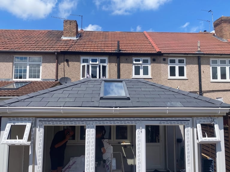 Modern white conservatory extension with slate roof attached to brick terraced house with windows