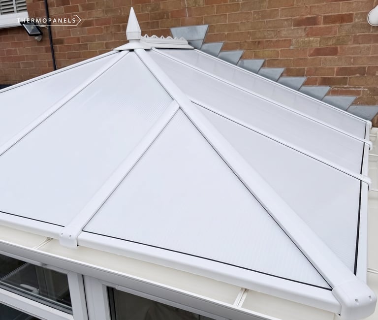 White pyramid-shaped glass roof lantern installed over a brick building with white frame and roof panels